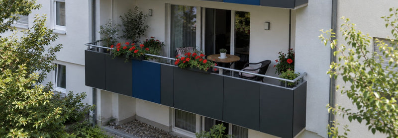 Moderne Balkonverkleidung mit HPL-Platten in Anthrazit und blauem Farbakzent an einem Mehrfamilienhaus – Deutsche Kunststoffbedachungen