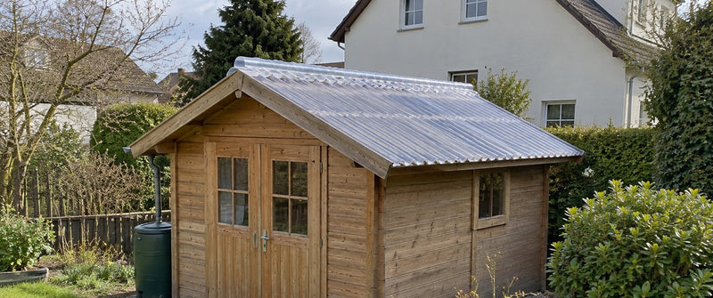 Gartenhaus mit Satteldach aus transparenten Wellplatten und passender Firsthaube im Garten – Deutsche Kunststoffbedachungen