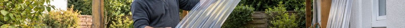 Heimwerker prüft eine klare Polycarbonat-Wellplatte vor dem Eindecken eines Holz-Carports – Deutsche Kunststoffbedachungen