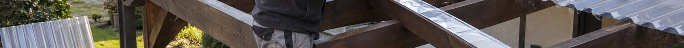 Heimwerker klebt Alu-Klebeband auf die Holzlatten eines Carports mit klaren Wellplatten – Deutsche Kunststoffbedachungen